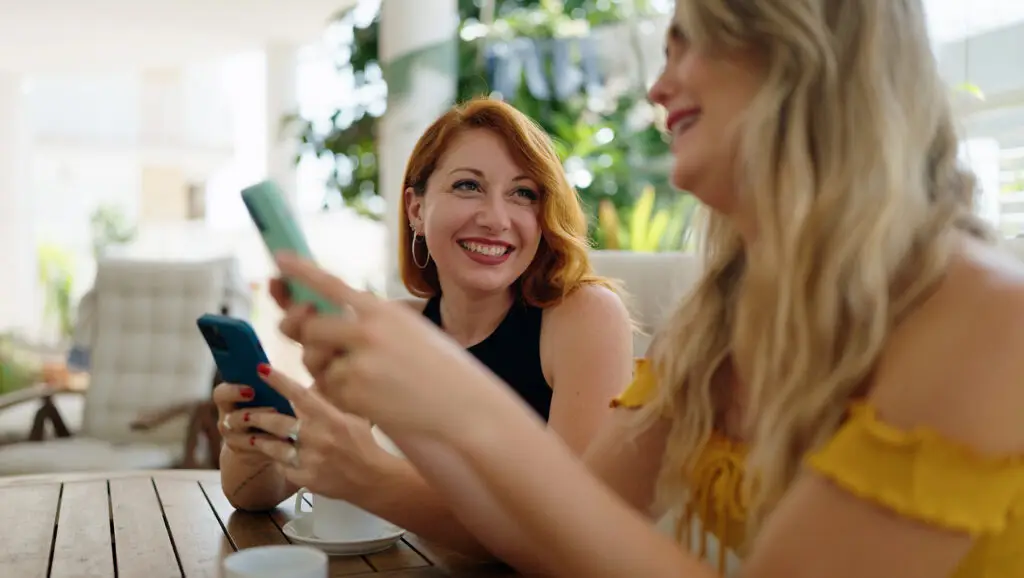 Two friends sharing a phone and talking
