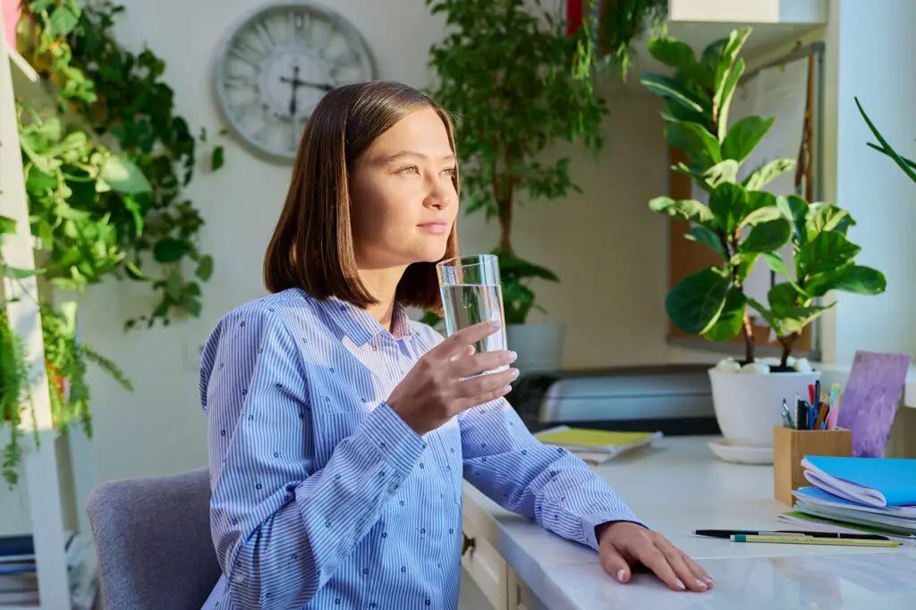 Woman drinking a glass of water at her desk