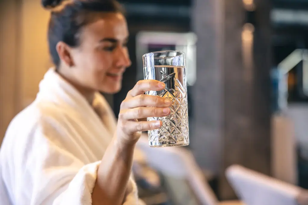 Woman in a bathrobe holding a glass of filtered water