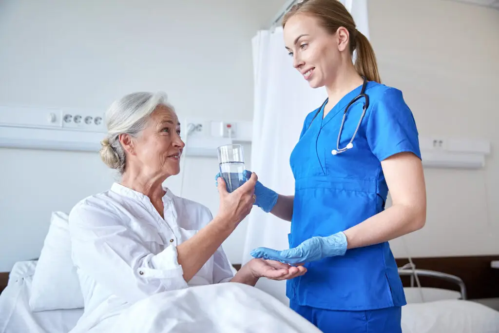Nurse giving a glass of water to an elderly patient